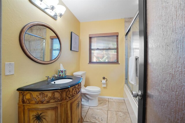 bathroom with toilet, vanity, shower / bath combination with glass door, and baseboards