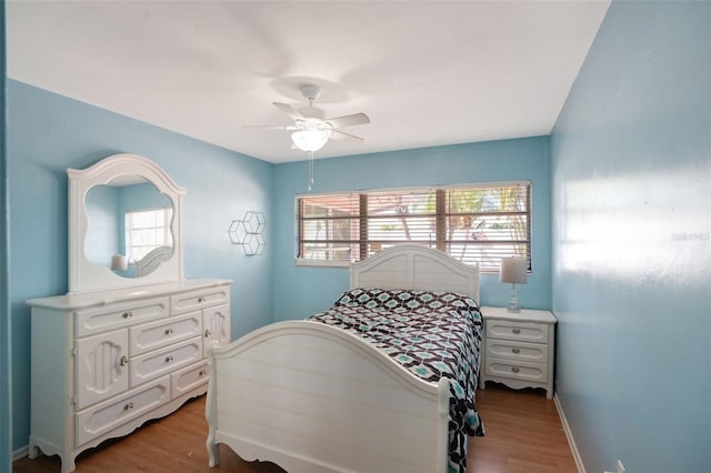 bedroom featuring wood finished floors, a ceiling fan, and baseboards