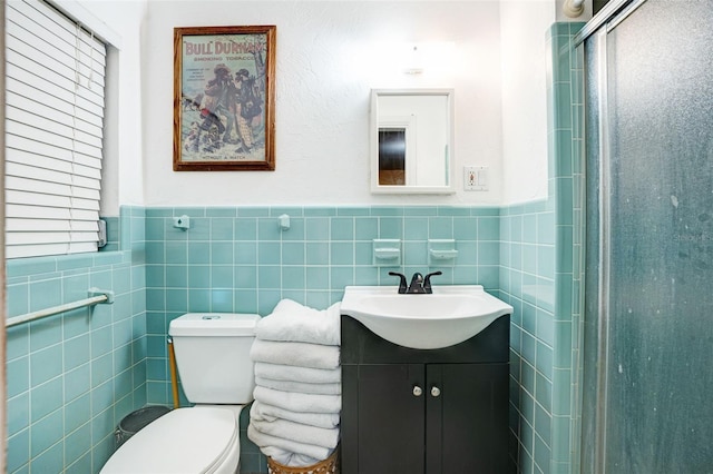 bathroom with vanity, a stall shower, a wainscoted wall, and tile walls