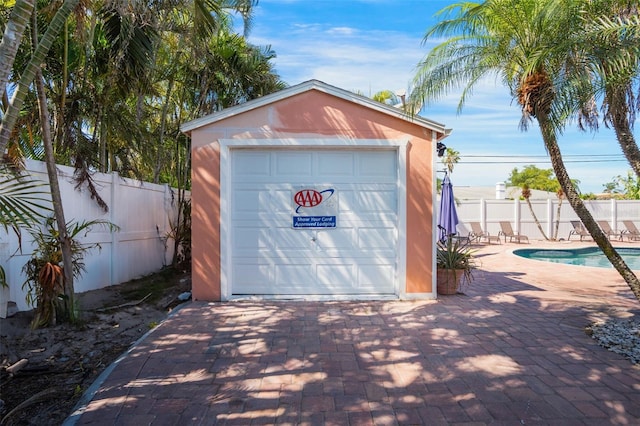 detached garage featuring fence and a fenced in pool