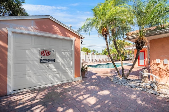 detached garage featuring fence and a fenced in pool