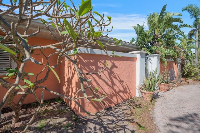 exterior space with stucco siding, fence, and a gate