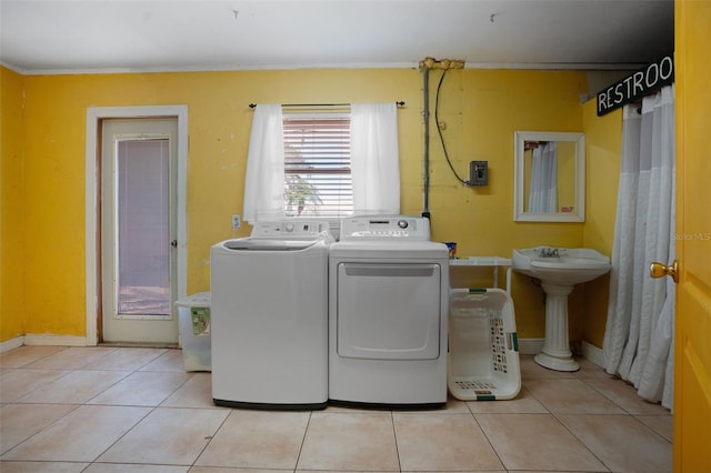 laundry area featuring laundry area, washer and clothes dryer, a sink, light tile patterned flooring, and baseboards