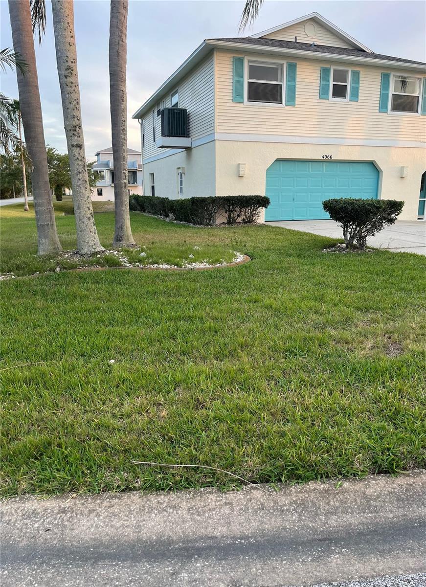 4066 Amberjack Dr, Hernando Beach, FL 34607 - view of property exterior featuring a lawn, driveway, cooling unit, and a garage