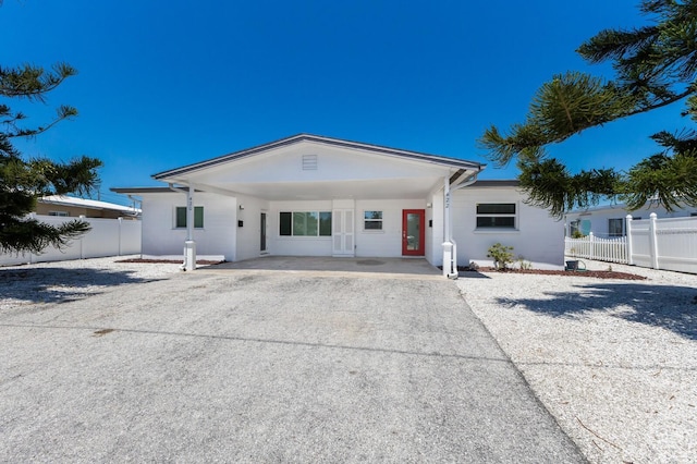 view of front of home with aphalt driveway, a carport, fence, and stucco siding
