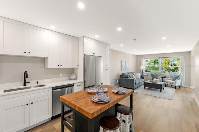 kitchen with light wood-type flooring, white cabinetry, visible vents, stainless steel appliances, and a sink