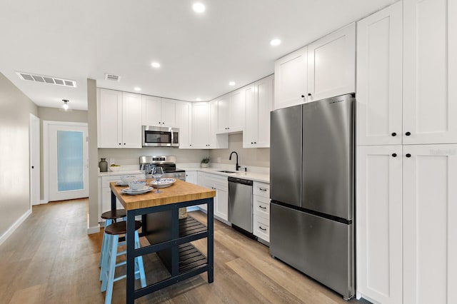 kitchen with light countertops, light wood-style floors, visible vents, appliances with stainless steel finishes, and a sink