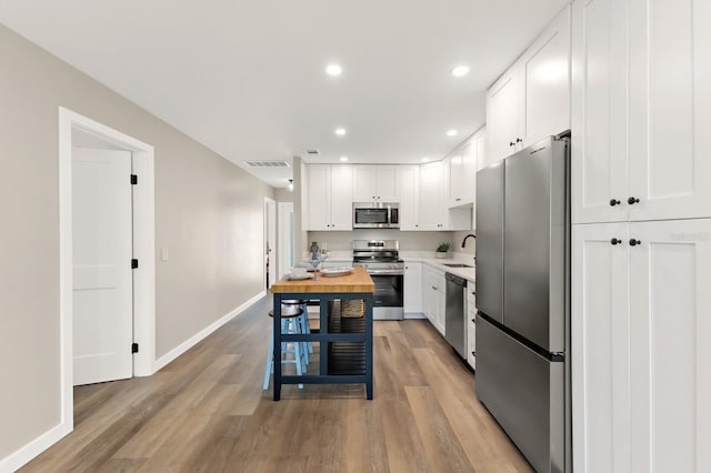 kitchen with butcher block countertops, baseboards, visible vents, appliances with stainless steel finishes, and a sink