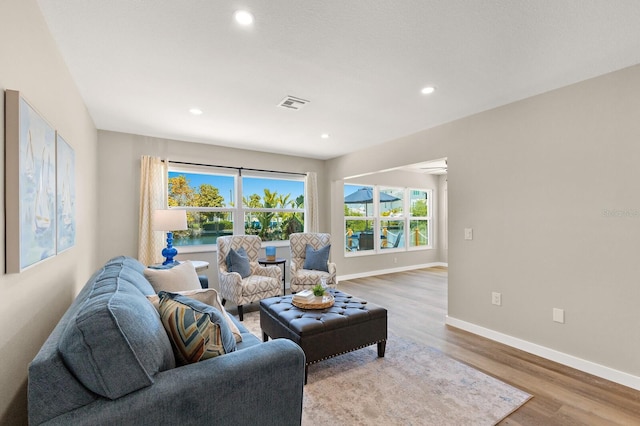 living room with recessed lighting, visible vents, baseboards, and wood finished floors