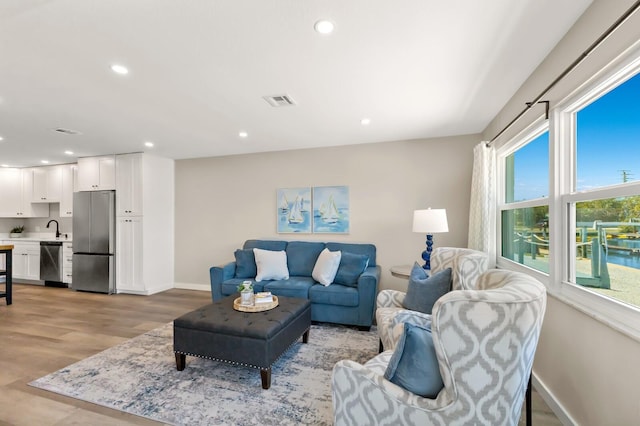 living room with light wood-style flooring, visible vents, baseboards, and recessed lighting