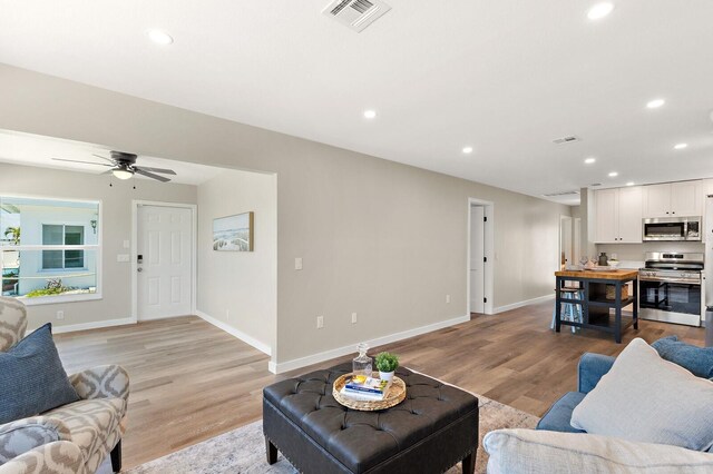 living area with light wood-style flooring, visible vents, and recessed lighting
