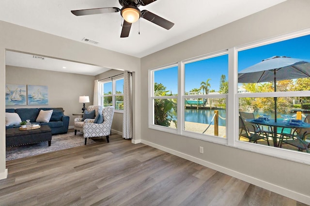 living area with wood finished floors, baseboards, visible vents, and a water view