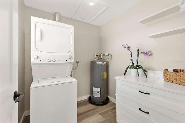laundry room with laundry area, light wood-style flooring, electric water heater, stacked washing maching and dryer, and baseboards