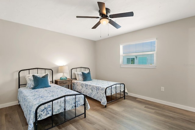 bedroom with ceiling fan, baseboards, and wood finished floors