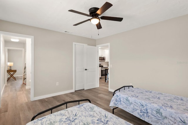 bedroom featuring visible vents, baseboards, a ceiling fan, and wood finished floors