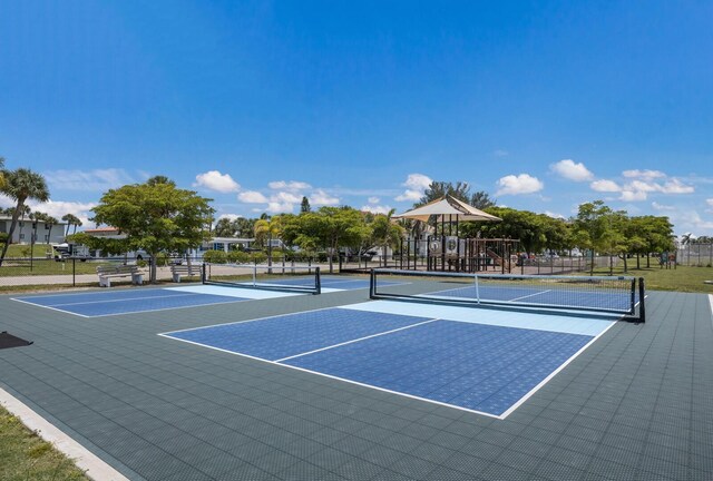 view of tennis court featuring community basketball court, fence, and playground community