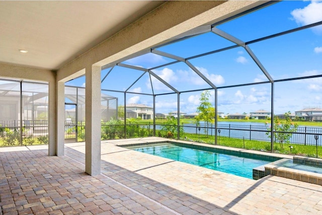 view of pool featuring a patio, a pool with connected hot tub, fence, and a water view