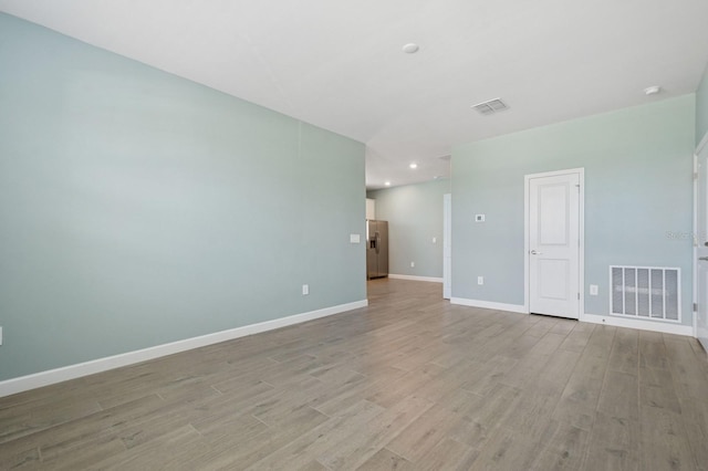 spare room with visible vents, light wood-style flooring, and baseboards