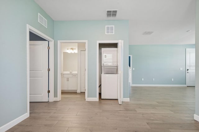 unfurnished bedroom featuring stacked washer / dryer, visible vents, and light wood-style flooring