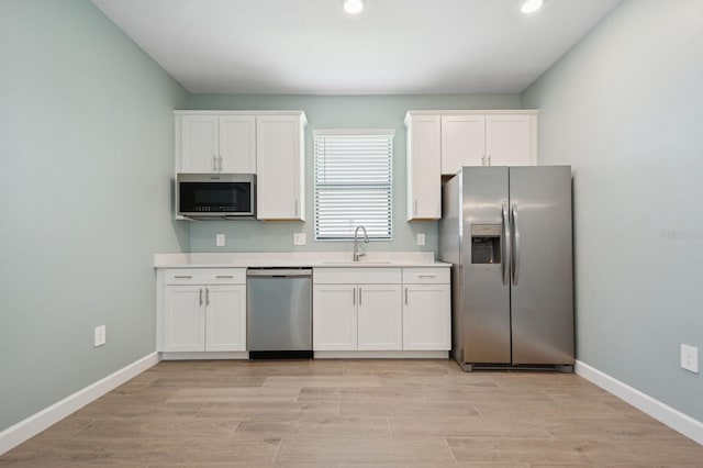 kitchen with recessed lighting, light countertops, white cabinetry, stainless steel appliances, and a sink