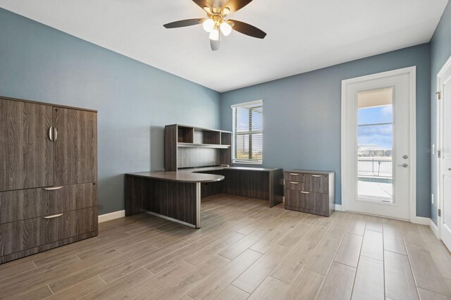 unfurnished office with baseboards, a ceiling fan, and light wood-style floors