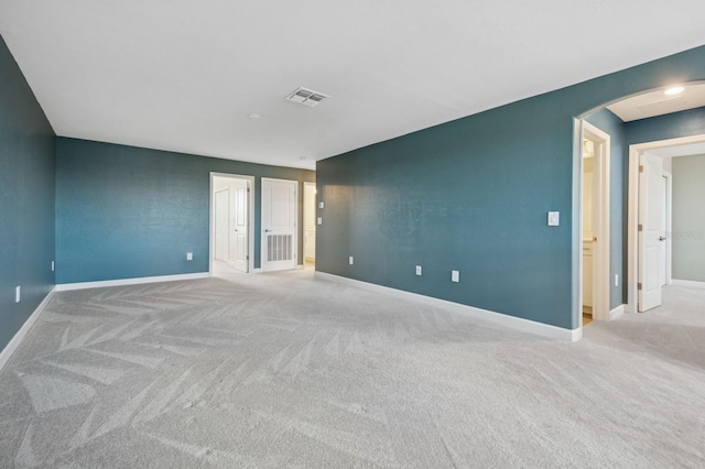 empty room featuring visible vents, baseboards, arched walkways, and carpet