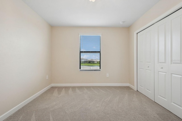 unfurnished bedroom with a closet, carpet flooring, and baseboards