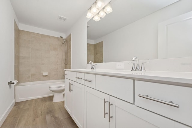 full bath featuring a sink, double vanity, toilet, visible vents, and wood finished floors