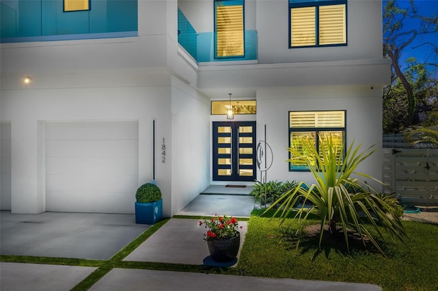 doorway to property with an attached garage, a porch, and stucco siding