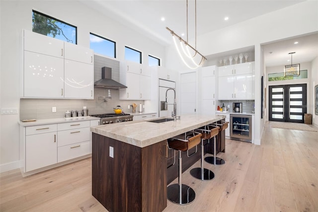 kitchen with modern cabinets, wall chimney exhaust hood, and a sink