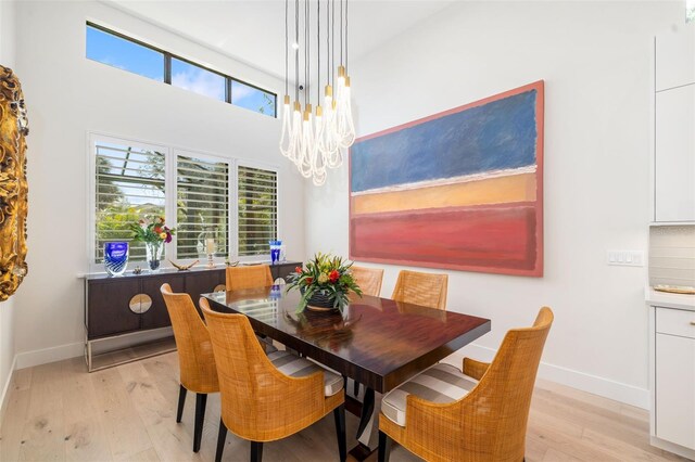 dining space with a chandelier, light wood-style floors, and baseboards