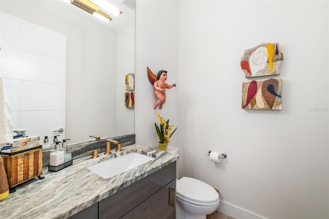 bathroom featuring baseboards, vanity, and toilet