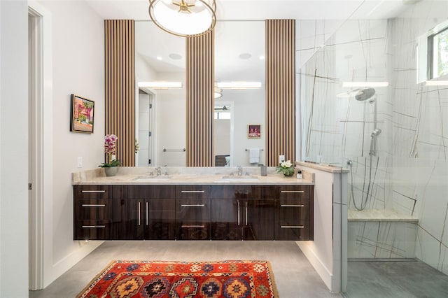 full bath with baseboards, a sink, a marble finish shower, and double vanity