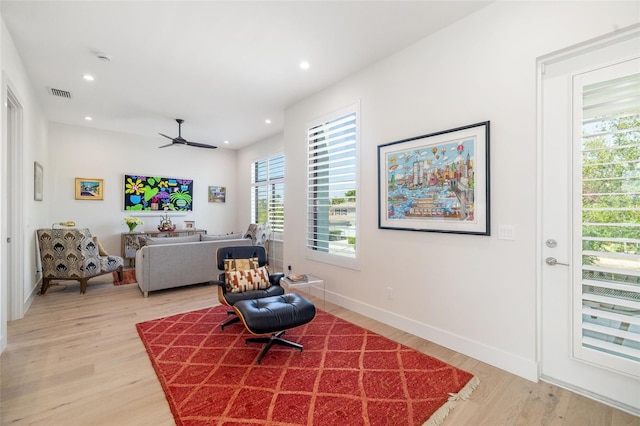 living area featuring a ceiling fan, visible vents, light wood-style floors, and a healthy amount of sunlight