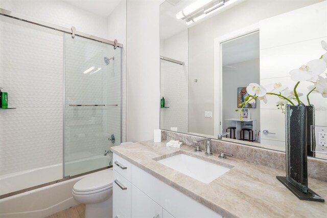 bathroom with vanity, shower / bath combination with glass door, and toilet