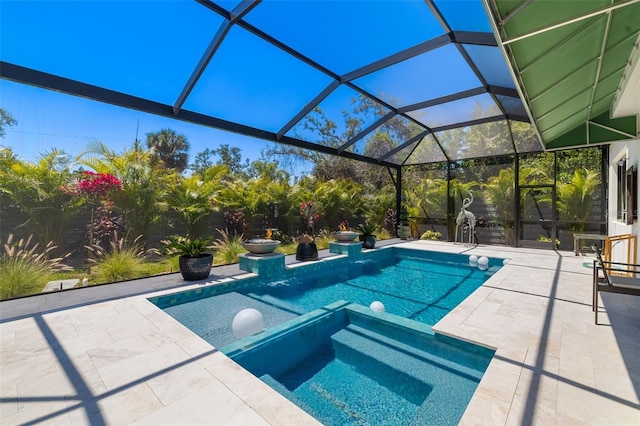 view of pool featuring glass enclosure, a pool with connected hot tub, and a patio