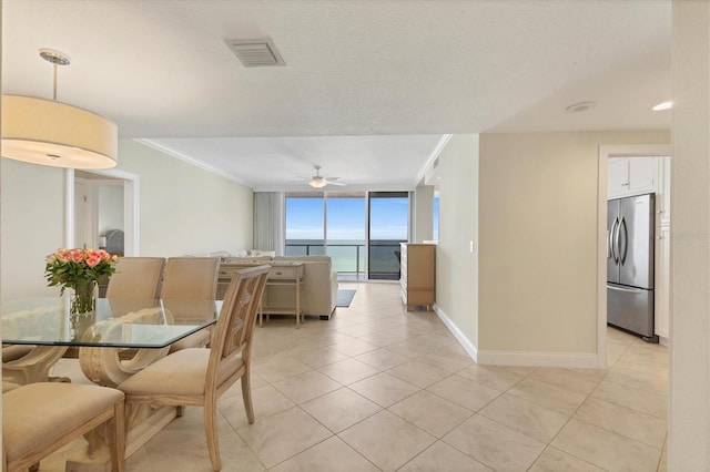 dining room with visible vents, ornamental molding, a wall of windows, baseboards, and light tile patterned floors