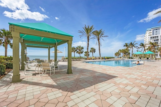 community pool with a water view, a patio, and a gazebo