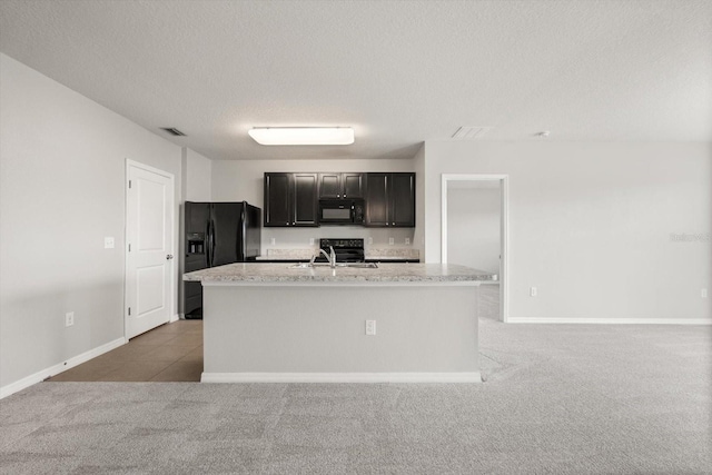 14914 Flowing Gold Dr, Bradenton, FL 34212 - kitchen with black appliances, light colored carpet, a sink, a textured ceiling, and a center island with sink