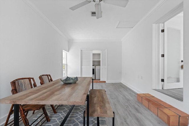 dining room featuring independent washer and dryer, crown molding, wood finished floors, ceiling fan, and attic access