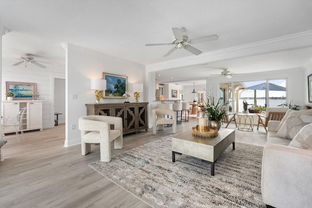 living area featuring ornamental molding, ceiling fan, light wood-style flooring, and baseboards