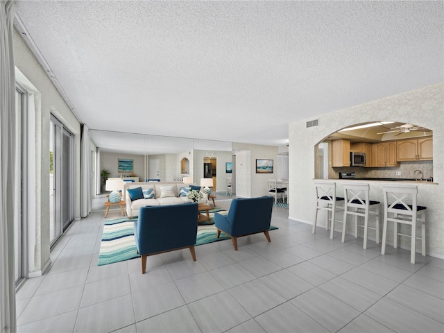living area featuring a textured ceiling, arched walkways, and light tile patterned flooring