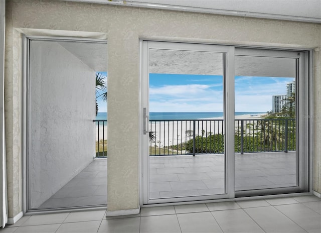 entryway with a water view, a textured wall, and tile patterned flooring