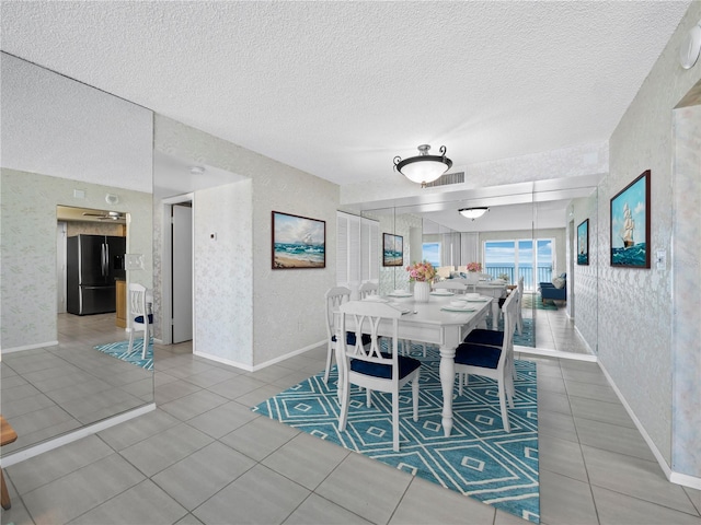 tiled dining space featuring wallpapered walls, baseboards, and a textured ceiling