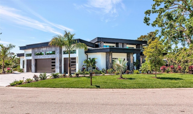 view of front of house with a garage, driveway, a front yard, and stucco siding