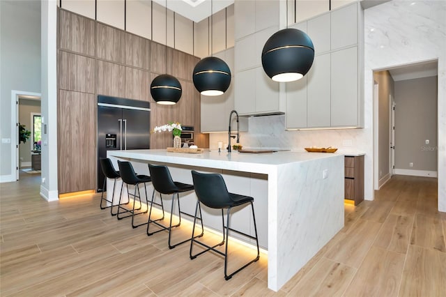 kitchen with modern cabinets, a breakfast bar, a large island, and built in refrigerator