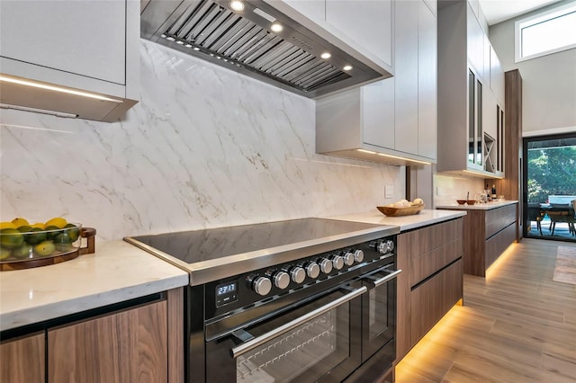 kitchen with modern cabinets, custom exhaust hood, double oven range, and light countertops