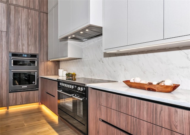 kitchen with modern cabinets, multiple ovens, and black / electric stove