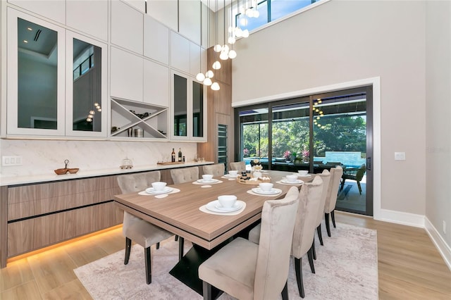 dining room featuring baseboards, a high ceiling, and light wood-style flooring