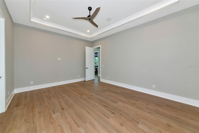 unfurnished room featuring light wood finished floors, a ceiling fan, baseboards, and a raised ceiling